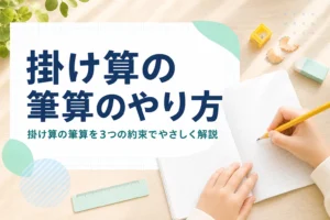 机の上の方眼ノートと鉛筆を持つ子どもの手元と、掛け算の筆算のやり方を紹介する記事タイトル